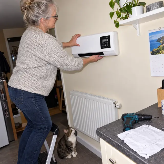 Woman fitting a plug-in wall heater herself, no electrician